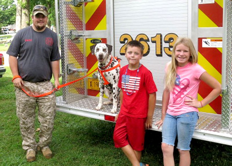 Randy Scates, 9, of Sulphur Springs, and his cousin Elizabeth Sanders, 10, of Gravette, paused after stopping to pet Blaze, the Sulphur Springs Fire Department's mascot. The dalmatian and his handler, Zach Bequette (left), have been associated with the fire department since Zach moved back to Sulphur about a year ago.