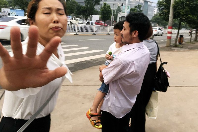 Hua Xiaoqin (left), sister of Chinese labor activist Hua Haifeng, tries to block a reporter from approaching him as Haifeng, carrying his son, leaves a police station Wednesday in Ganzhou in southern China’s Jiangxi province. 