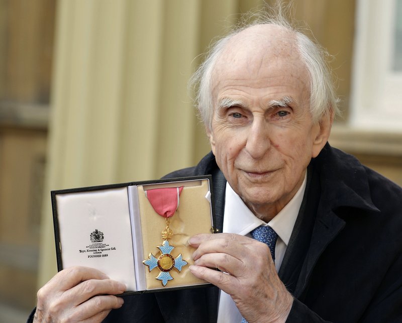 FILE - In this Oct. 27, 2015 file photo, Michael Bond, the creator of Paddington Bear, poses with his Commander of the Order of the British Empire (CBE). Publisher HarperCollins says Michael Bond, creator of globe-trotting teddy Paddington bear, died on Tuesday June 27, 2017, aged 91. (John Stillwell/PA via AP)