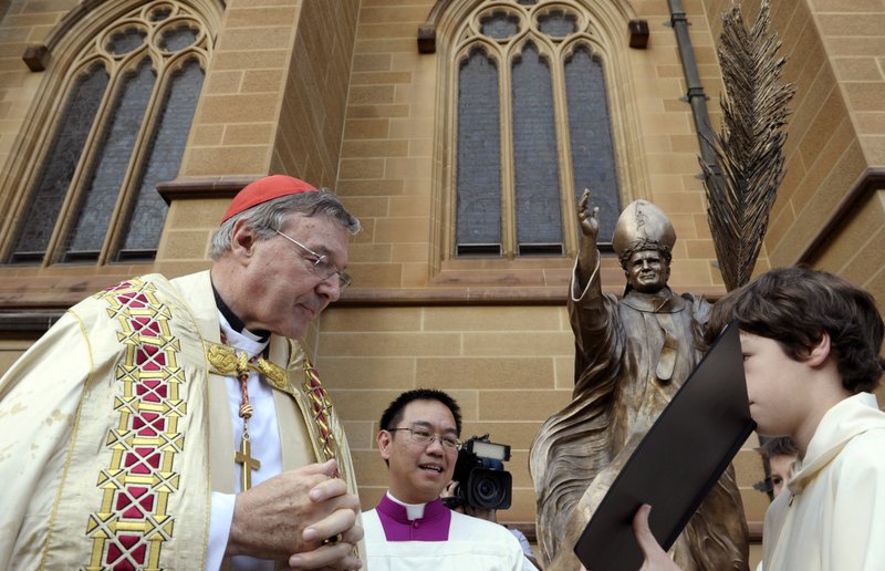 FILE - In this May 1, 2011 file photo, Cardinal George Pell, left, reads a bible during the blessing of a statue of John Paul ll at St Mary's Cathedral in Sydney, Australia. Australian police say they are charging Pell with historical sexual assault offenses. (AP Photo/Rob Griffith, File)