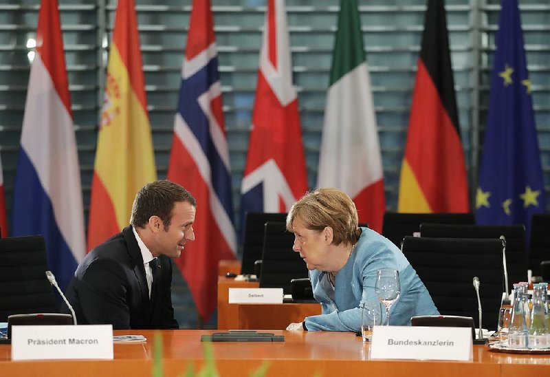 French President Emmanuel Macron (left) talks with German Chancellor Angela Merkel on Thursday in the chancellery in Berlin before a gathering of European leaders regarding the G-20 summit next week.  