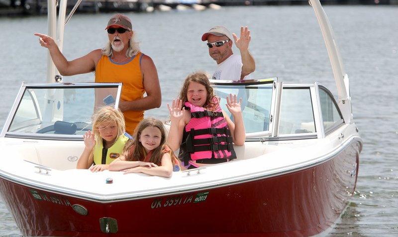 NWA Democrat-Gazette/DAVID GOTTSCHALK Tim Osborn (left) gives directions as Jerry Blaich and Annallen Blaich (from left), 7, Presley Blaich, 11, and Julianne Blaich, 10, wave to their trailer Thursday at the Prairie Creek boat ramp as they prepare to spend the afternoon on Beaver Lake. Osborn said the girls have their life jackets on at all times when on the boat except when they are reapplying sunscreen.