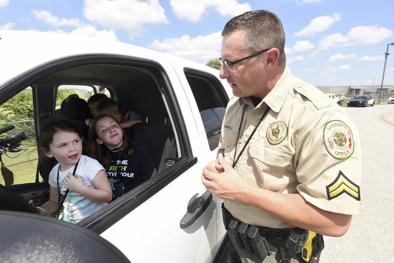 Cpl. Ralph Bartley talks to youngsters during a mock traffic stop, part of demonstrations Wednesda for youths in the Police Athletic League in Bentonville.