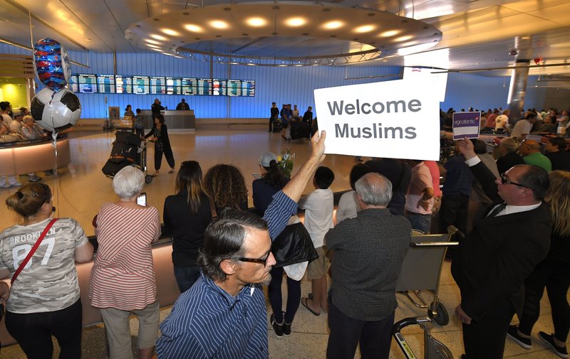 John Wider holds up a sign welcoming Muslims in the Tom Bradley International Terminal at Los Angeles International Airport. A scaled-back version of President Donald Trump’s travel ban took effect Thursday evening, stripped of provisions that brought protests and chaos at airports worldwide in January yet still likely to generate a new round of court fights.  