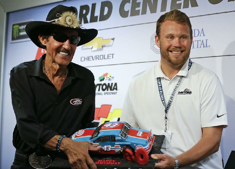 Chip Wile, right, president of Daytona International Speedway, presents Richard Petty with an 80th birthday cake in the shape of a race car during a NASCAR cup auto racing news conference at Daytona International Speedway, Friday, June 30, 2017, in Daytona Beach, Fla. 