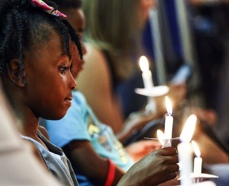 Naome Shelton, 5, of North Little Rock takes part in a downtown Little Rock candlelight vigil Saturday evening after the nightclub shooting earlier. Religious leaders spoke at the vigil for about half an hour.