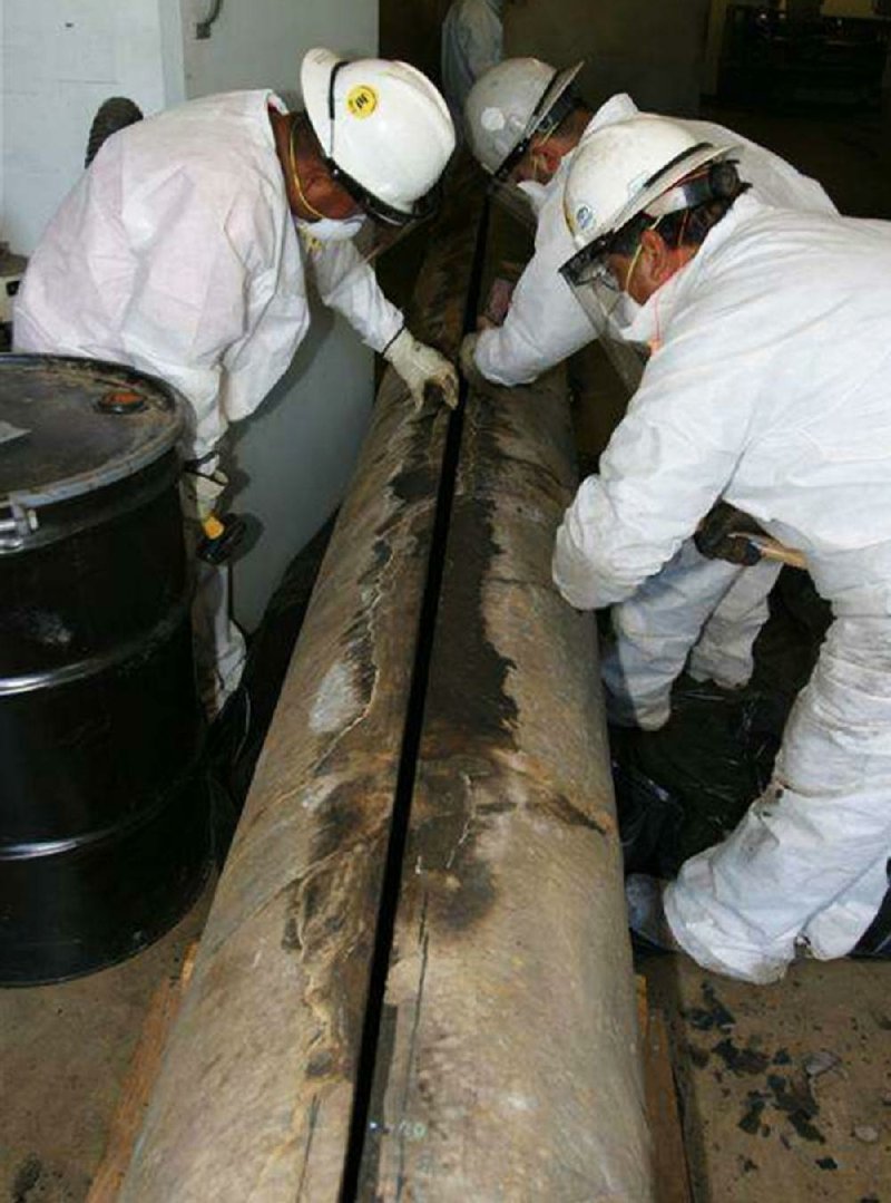 Technicians examine the cracked section of the Pegasus pipeline that spilled thousands of gallons of thick crude oil in a Mayflower neighborhood on Good Friday in 2013.