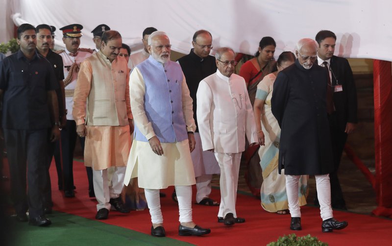 Indian Prime Minister Narendra Modi, center, Indian President Pranab Mukherjee, center right, and Indian Vice President Hamid Ansari, right, walk in a procession for a midnight session of parliament to launch the Goods and Services Tax (GST) in New Delhi, India, Friday, June 30, 2017. The single, nationwide tax starting Saturday replaces a complicated mix of state and federal taxes and will change the cost of nearly everything people buy. 