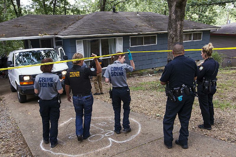 A member of the coroner’s office and Little Rock crime scene personnel cross a police barrier Sunday to investigate the city’s 29th homicide of the year. Naomi Estrada was found dead in her home at 46 Westmont Circle on Sunday morning.