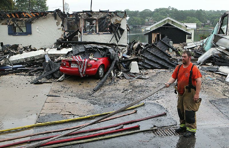 Lake Hamilton Fire Department volunteer Jeremy Hill wraps up fire hoses Sunday morning after battling a blaze overnight at a resort on Lake Hamilton in Garland County.