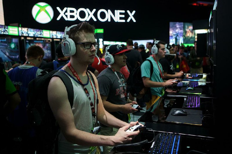 Attendees play a video game at the Microsoft Corp. booth during the E3 Electronic Entertainment Expo in Los Angeles on June 14. The company is about to announce a global layoff, sources have told several news outlets.
