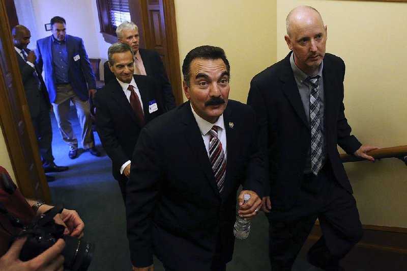 New Jersey Democratic Assembly Speaker Vincent Prieto (center) is accompanied by Horizon Blue Cross Blue Shield of New Jersey Chairman and CEO Bob Marino (right) at the Statehouse on Monday, in Trenton, N.J.