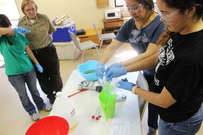 Lydia Leatherwood (from left), wipes her brow as Arkansas State Parks Interpreter Betty Coors watches Kazandra Wilson (second from right) and daughter Ana Wilson pour lye into water during the Lye Soap Making Workshop at the Plantation Agriculture Museum in Scott.
