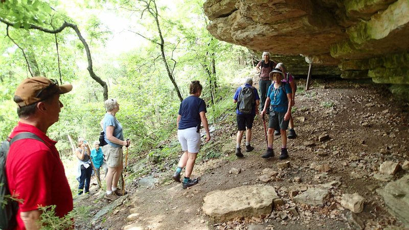 Hikers explore a bluff shelter June 8 along the Bench Rock Trail near Beaver Lake at Indian Creek park. The 1.1-mile oblong loop meanders through forest and along bluffs.
