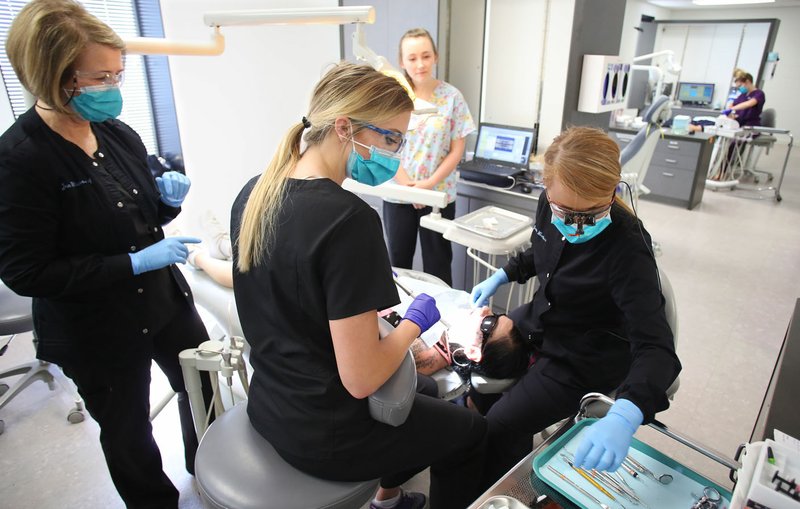 Jan Willams (from left), dental assistant, Jordan Gall, pre-dental student volunteer, and Kayla Garibaldi, pre-dental student volunteer, assist Wednesday dentist Jenna Waselues with fillings on a patient at WelcomeHealth in Fayetteville.