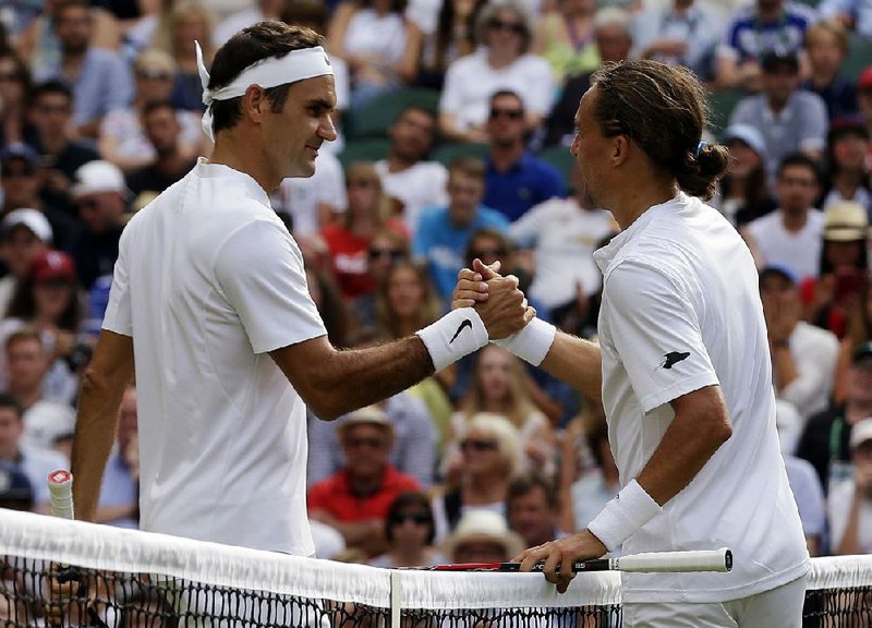 Alexandr Dolgopolov (right) greets Roger Federer at the net after Dolgopolov was forced to quit their first-round Wimbledon match in the second set Tuesday because of a right ankle injury. Federer was leading 6-3, 3-0 before Dolgopolov retired.