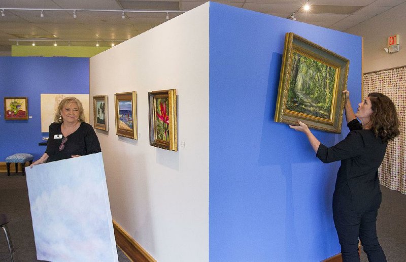 Art on the Green gallery director Brenda McClain (left) and curator of education Kelly Booy set up an exhibit Thursday in Conway. 