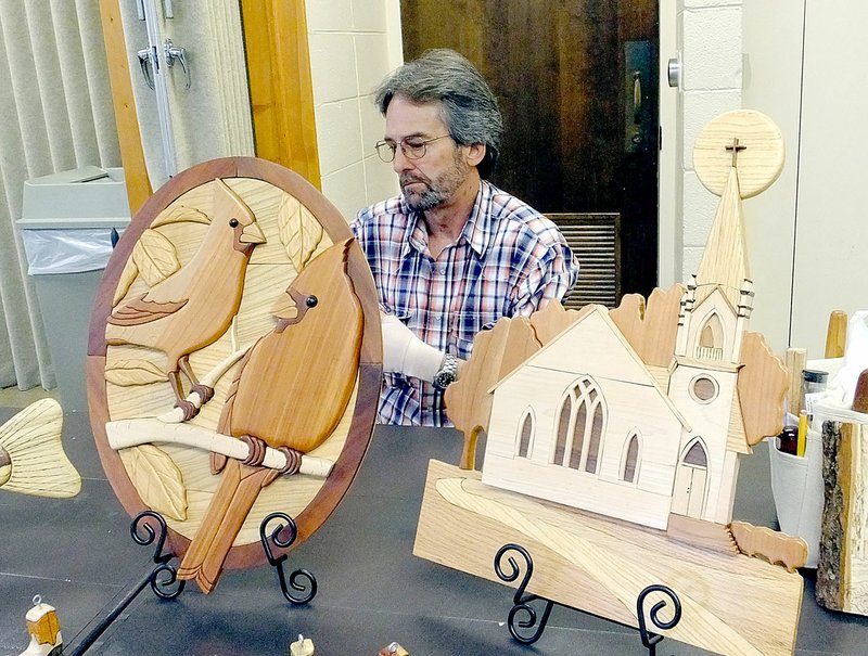 Lynn Atkins/The Weekly Vista Kevin Attleson works on a new Intarsia piece behind two of his completed pieces as the Bella Vista Woodcarvers Show prepares for their Artistry in Wood Show.