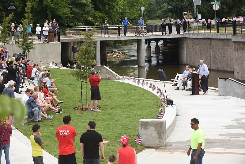 Doug Sprouse (right), Springdale mayor, comments during the dedication of Walter Turnbow Park in downtown Springdale. The park is situated along Mill Creek on the north side of Emma Avenue. (NWA Democrat-Gazette/FLIP PUTTHOFF)