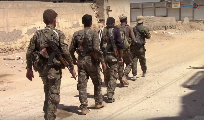 This frame grab from video released Tuesday, July 4, 2017, and provided by Furat FM, a Syrian Kurdish activist-run media group, shows U.S.-backed Syrian Democratic Forces (SDF) fighters in the eastern side of Raqqa, Syria. The SDF forces have breached the wall around Raqqa's Old City, the U.S. military said Tuesday, marking a major advance in the weeks-old battle to drive Islamic State militants out of their self-declared capital. (Furat FM, via AP)