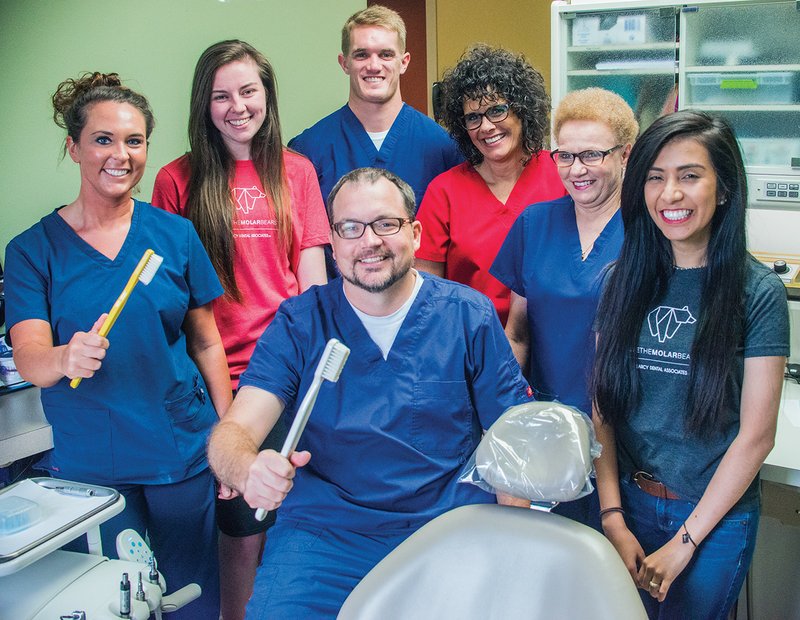 Standing around Dr. Todd Wyatt, center, at Searcy Dental Associates as they prepare for the 21st annual A Day of Caring are, from left, Courtney Laire, dental assistant; Erin Whitley, administrative assistant; Kohl Blickenstaff, intern; Kristen Davidson, dental hygienist; Colette Owens, dental assistant; and Kenia Munoz, administrative assistant.