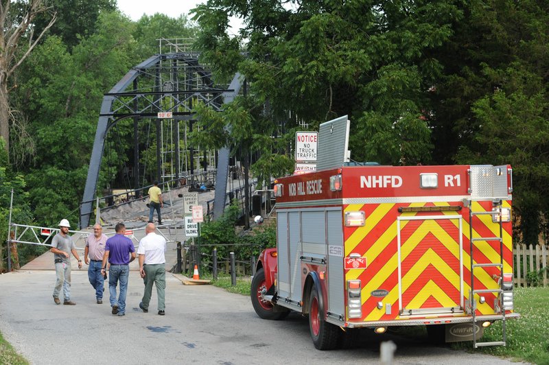 Emergency personnel work together with construction crews Friday at the War Eagle Bridge as they search for a person believed to be in the water beneath the bridge.