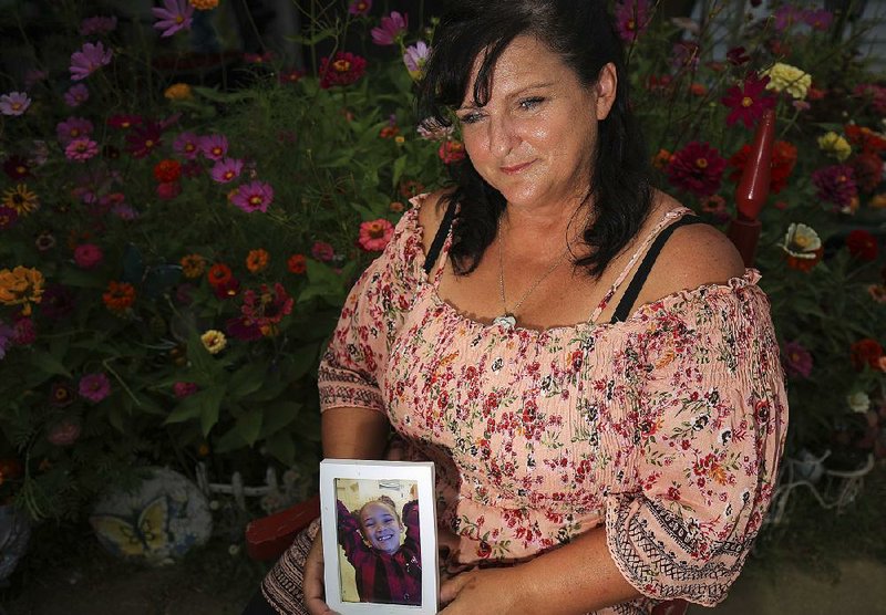 Brenda Wezowicz holds a photo of her granddaughter, Karma Wezowicz, as she sits in front of the butterfly garden they had planned together. 