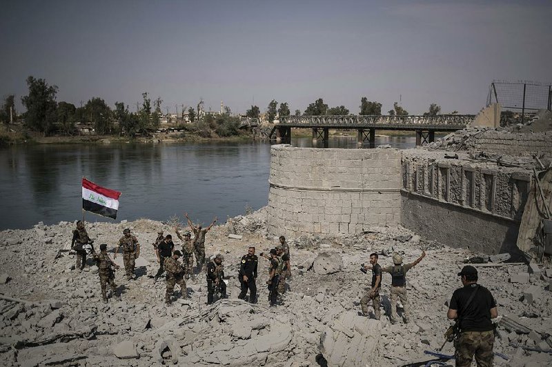 Iraqi soldiers celebrate Sunday after reaching the bank of the Tigris River as their fight against Islamic State militants continues in the Old City section of Mosul.