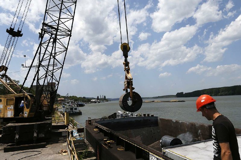 A worker directs a crane lifting a roll of coiled steel plate onto a barge in Smederevo, east of Belgrade, Serbia, on June 29. Hebei Iron & Steel’s $52 million purchase of the Steelworks Smederevo is part of China’s effort to project influence and gain access to the European market.