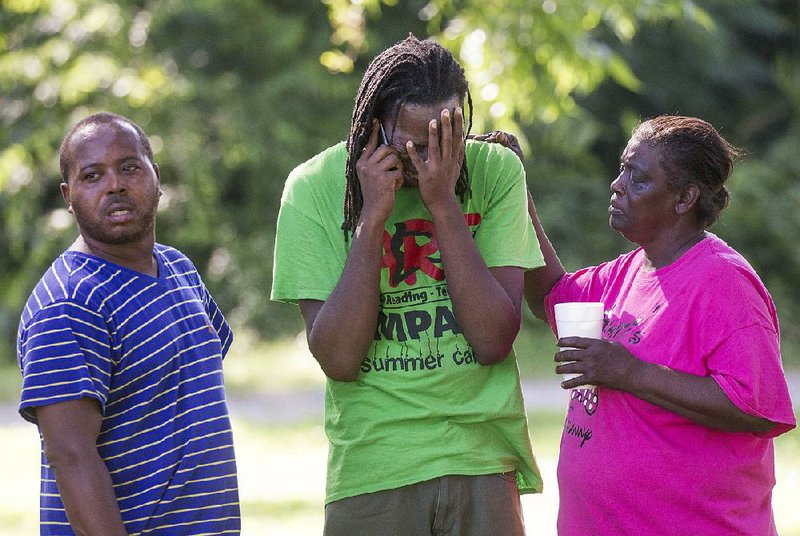 The brother (center) of an unidentifi ed man who shot and killed himself during a police standoff in North Little Rock on Monday afternoon is consoled by neighbors in the 800 block of North Cypress Street.