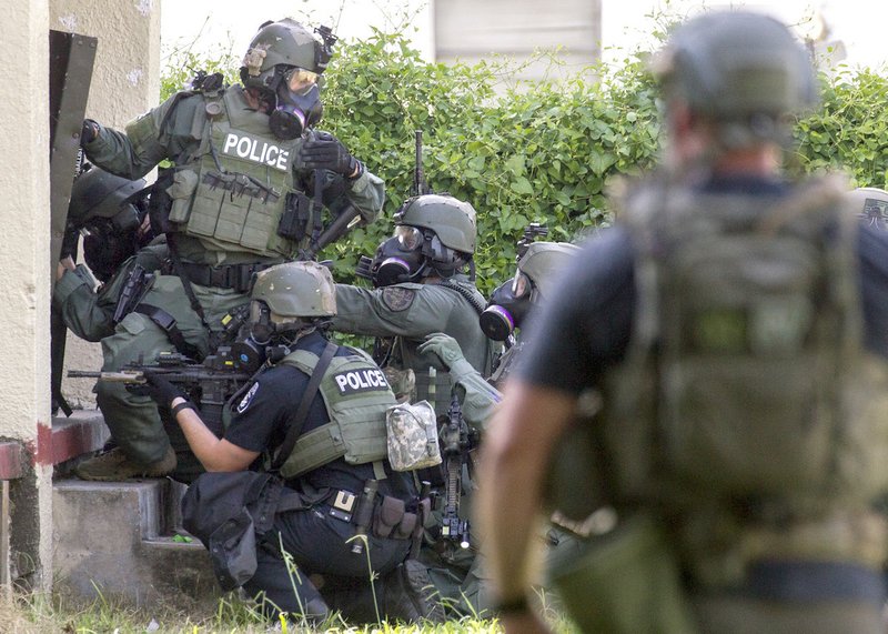 The North Little Rock Police Department's special response team on Monday, July 10, 2017, advances toward the door of a two-story residential building in the 800 block of North Cypress Street. A suspect sought on a rape charge was later found dead inside of a self-inflicted gunshot wound after an hours-long standoff.