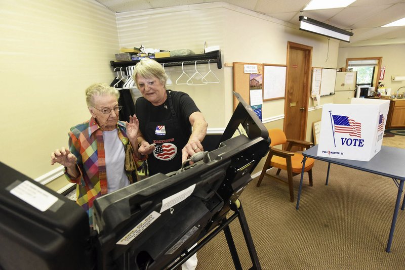 NWA Democrat-Gazette/FLIP PUTTHOFF Crystal Parker (left) votes Tuesday in the Beaver Lake Fire Department dues election with help from poll worker Cathy Beck.