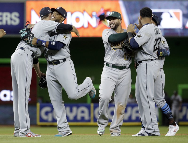 American League's Seattle Mariners Robinson Cano (22), second from left, is hugged by Cleveland Indians pitcher Andrew Miller, after winning the MLB baseball All-Star Game, Tuesday, July 11, 2017, in Miami. Cano hit a home run in the tenth inning to win the game. The American League defeated the National league 2-1. (AP Photo/Lynne Sladky)