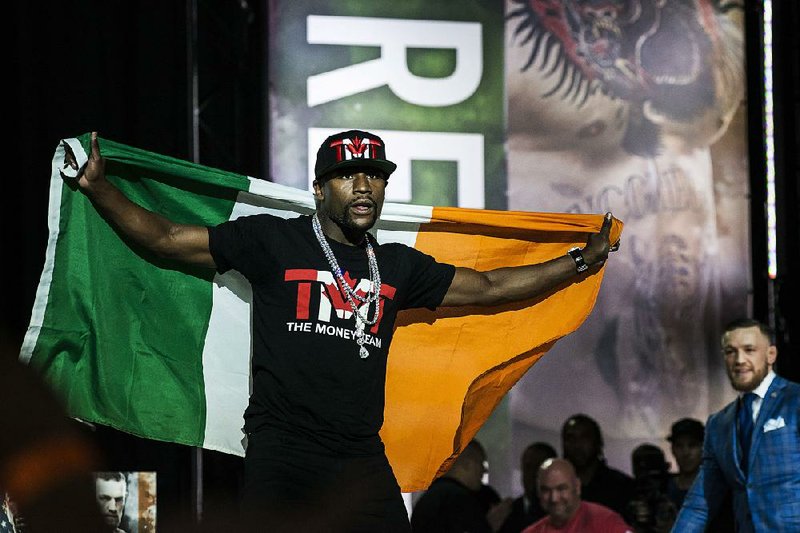 Floyd Mayweather, left, taunts Conor McGregor by wearing the Irish flag during a promotional stop in Toronto on Wednesday, July 12, 2017, for their upcoming boxing match in Las Vegas. 