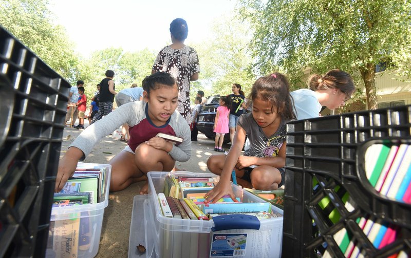 Damina Mea, 8 (left), and Ronitha Bungitak, 9, look through books Tuesday provided by Tillery Elementary School in Rogers for summer reading.