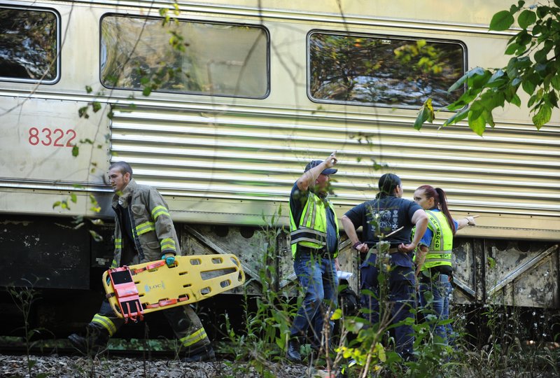 Ron Sparks (center), chief of the Arkansas & Missouri Railroad police, speaks to members of his staff as a firefighter carries a piece of emergency equipment after an accident involving an A&M train Oct. 16, 2014, south of West Fork.