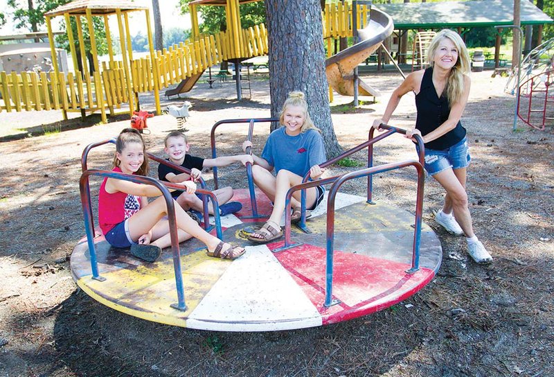 Gurdon Mayor Sherry Kelley pushes, from left, Blaise Childres, Triton Swayze and Kenzie Harper on the merry-go-round at the Gurdon City Park. The park is the city’s only park and is on the outskirts of town, highlighting the need for a park more central to the city. Kelley wrote and received a grant on behalf of Gurdon to build a park at City Hall.