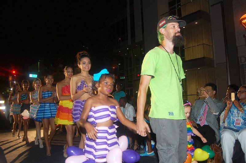Johnathan “Balloonatic” Darden holds the hand of a young model during the finale of his July 21, 2016, Little Rock Fashion Week segment. Guests of Little Rock Fashion Week: The Finale are asked to add some green to their attire in memory of Darden, a Shreveport, La. Army veteran who embraced the color in his fight for veterans’ rights. He died in May. 