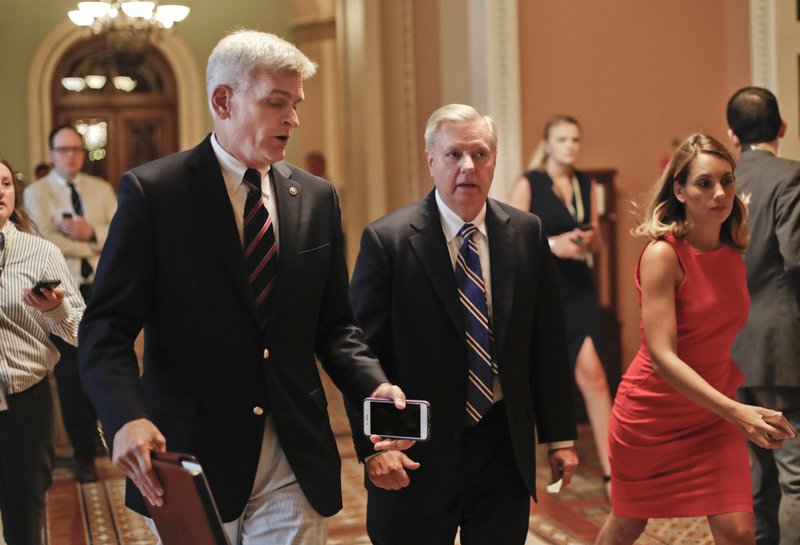 Sen. Bill Cassidy, R-La., left, and Sen. Lindsey Graham, R-S.C., right, talk while walking to a meeting on Capitol Hill in Washington Thursday, July 13, 2017. Senate Majority Leader Mitch McConnell of Ky. plans to roll out the GOP's revised health care bill, pushing toward a showdown vote next week with opposition within the Republican ranks. (AP Photo/Pablo Martinez Monsivais)