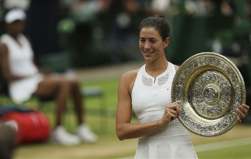 Spain's Garbine Muguruza, right, holds the winners trophy after defeating Venus Williams of the United States, left, in the Women's Singles final match on day twelve at the Wimbledon Tennis Championships in London Saturday, July 15, 2017. 