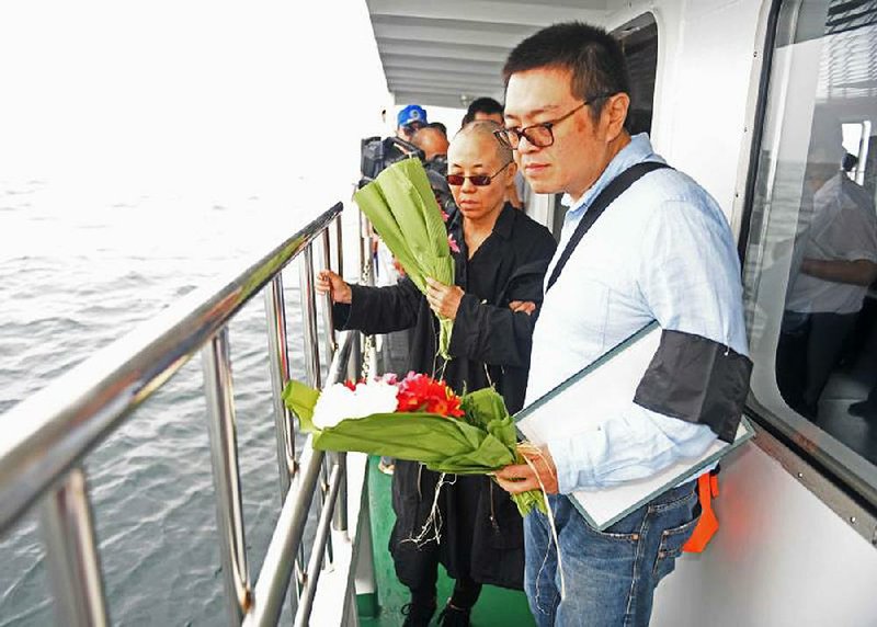 Liu Xia (left), the widow of Chinese political dissident and Nobel Peace Prize laureate Liu Xiaobo, and her brother carry "owers Saturday as they scatter the laureate’s ashes at sea off the northeastern China coast. The proceedings were closely orchestrated by the Chinese government.