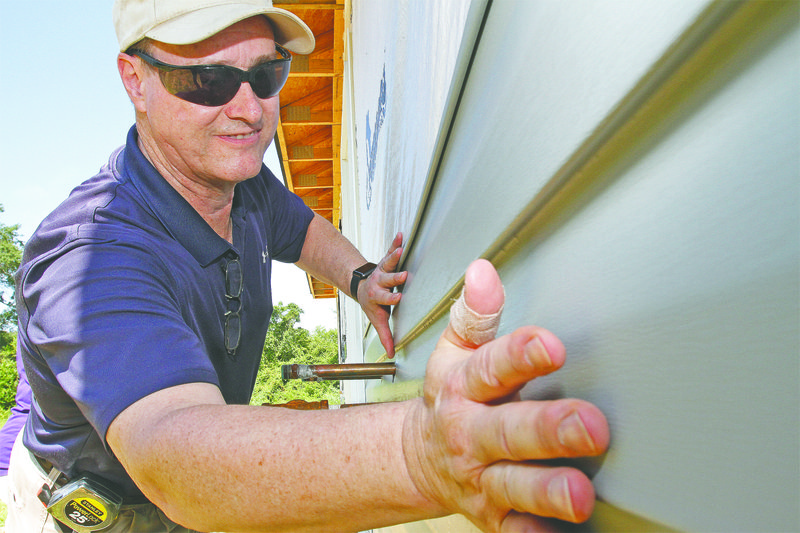 Volunteers: Habitat for Humanity volunteer Tim Fleming places siding onto a house on West Second Street in El Dorado on Saturday. 