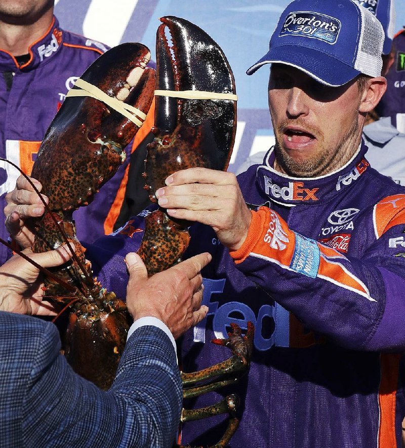 Denny Hamlin reacts as he is handed a lobster after winning Sunday’s race at New Hampshire Motor Speedway.