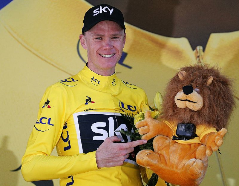 Britain's Chris Froome, wearing the overall leader's yellow jersey, points at the small camera attached to the yellow jersey's mascot on the podium of the fifteenth stage of the Tour de France cycling race over 189.5 kilometers (117.8 miles) with start in Laissac-Severac l'Eglise and finish in Le Puy-en-Velay, France, Sunday, July 16, 2017. 