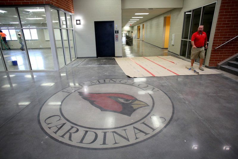 Jon Purifoy, principal at Farmington High School, walks Friday past the school emblem on the floor in the new Farmington High School. Classes will be begin at the school this August.