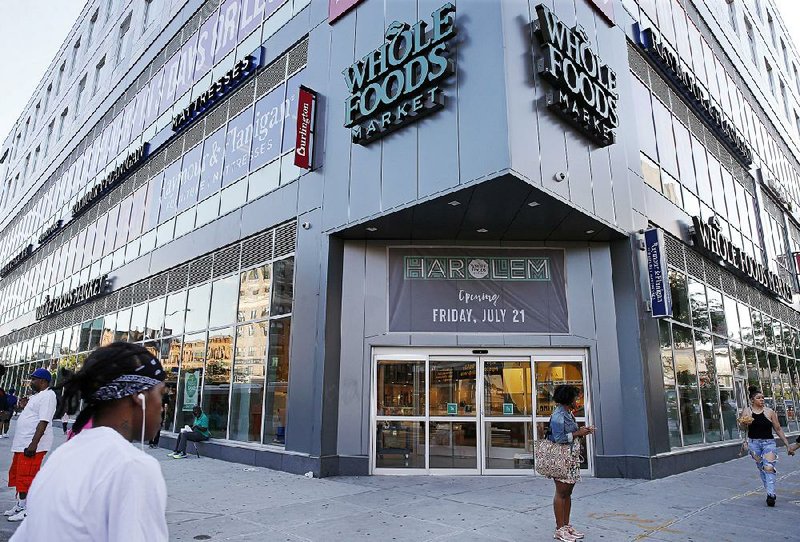 Pedestrians stand outside a Whole Foods Market set to open on West 125th Street in Harlem on Friday. Amazon.com’s purchase of Whole Foods for $13.7 billion last month was a sign the e-commerce giant is serious about becoming a player in the grocery industry.