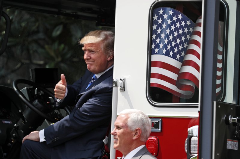 President Donald Trump, accompanied by Vice President Mike Pence, gives a thumbs-up, from the cabin of a Pierce firetruck during a "Made in America" product showcase featuring items created in each of the U.S. 50 states, Monday, July 17, 2017, at the White House in Washington. 