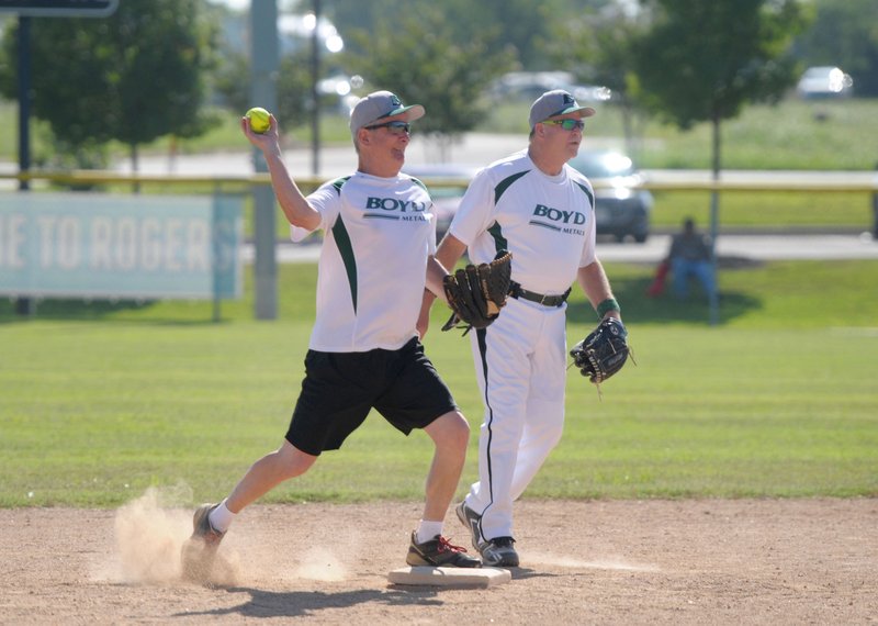 Robert Radford (left), of the Boyd Metals team from Fort Smith, throws to first for a double play Thursday as teammate Michael Taylor looks on during the Senior Softball U.S.A. Midwest Championships at the Rogers Regional Sports Park.