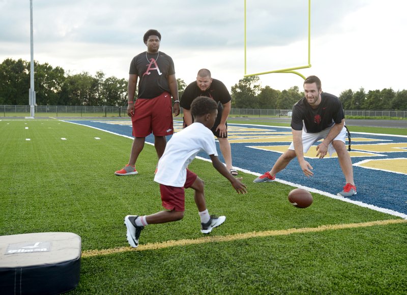 
Jalen Merrick (from left), Arkansas offensive lineman, Zach Rogers, Arkansas center, and Ty Storey, Arkansas quarterback, work drills with campers on Monday July 25, 2016 during the Bentonville West Wolverine Youth Football Camp at the school in Centerton. Over one hundred kindergarten through 8th grade students from the Bentonville district participated in the camp, with tours of the new school and visits by current and former Arkansas football players. 