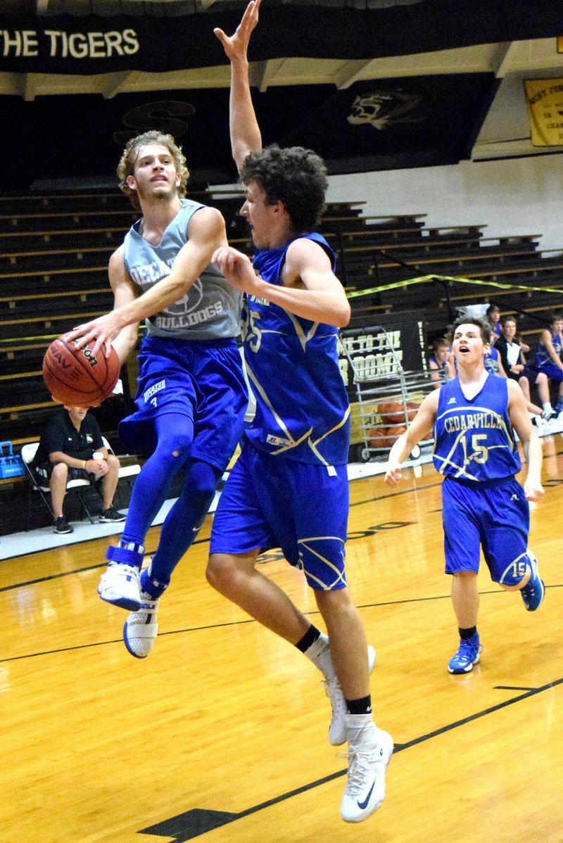 Photo by Mike Eckels Taylor Haisman (Decatur 3) goes airborne for a layup as a Pirates player tried to block his shot during the West Fork team camp between the Decatur Bulldogs and Cedarville Pirates at the Tiger Dome in West Fork July 14.